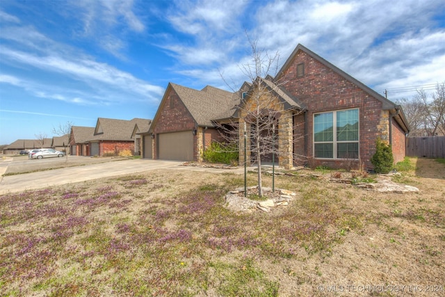 ranch-style home featuring brick siding, fence, concrete driveway, an attached garage, and a shingled roof