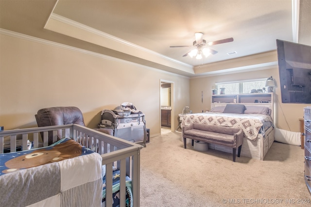 carpeted bedroom featuring ornamental molding, ensuite bath, a raised ceiling, and ceiling fan