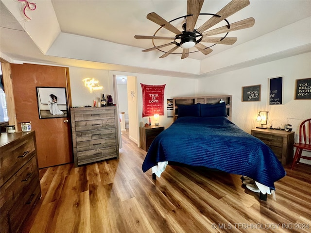 bedroom featuring ceiling fan, hardwood / wood-style flooring, and a raised ceiling