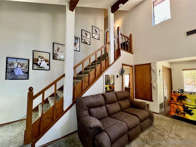 carpeted living room featuring beam ceiling and high vaulted ceiling