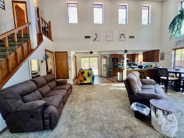 living room with a towering ceiling, a healthy amount of sunlight, and light hardwood / wood-style floors