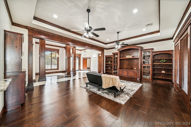 living room with ornate columns, dark hardwood / wood-style floors, and a tray ceiling