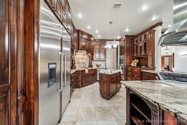 kitchen with hanging light fixtures, backsplash, appliances with stainless steel finishes, a kitchen island, and island range hood