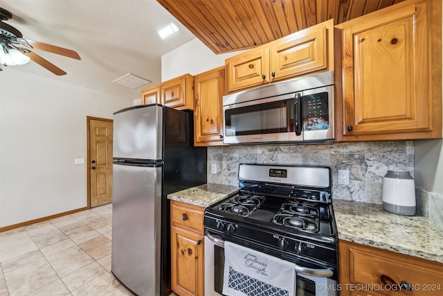 kitchen with light stone countertops, appliances with stainless steel finishes, decorative backsplash, and ceiling fan