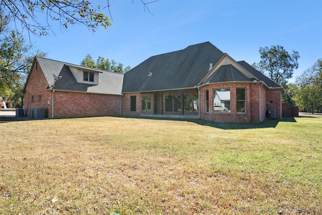 rear view of property featuring a yard and central air condition unit