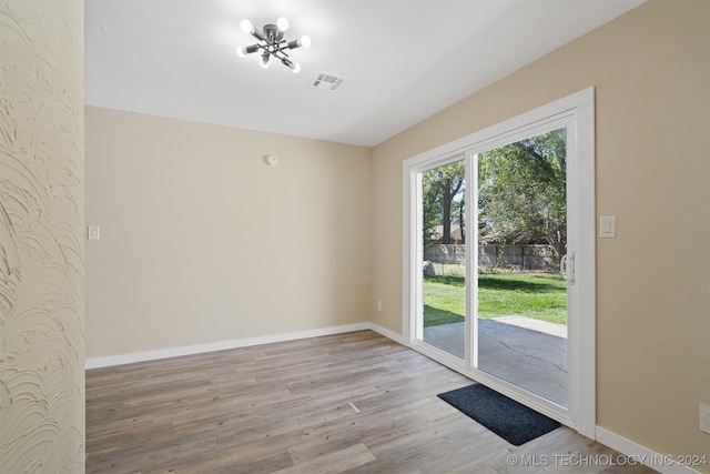 unfurnished room with an inviting chandelier and light wood-type flooring