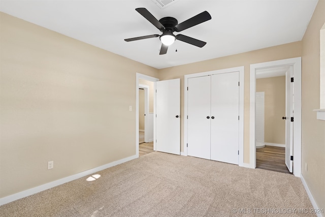 unfurnished bedroom with a closet, light colored carpet, and ceiling fan