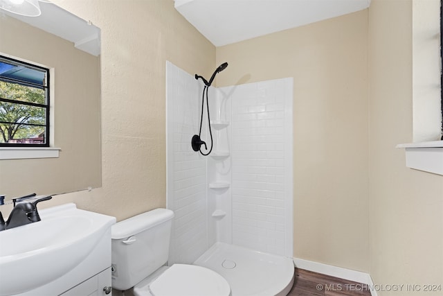 bathroom with vanity, a tile shower, hardwood / wood-style flooring, and toilet