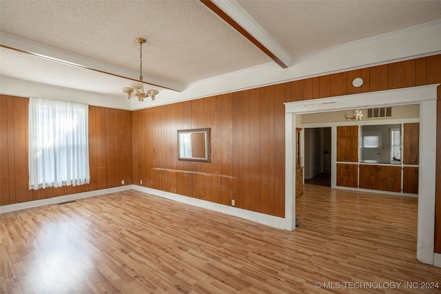 unfurnished room featuring beamed ceiling, wood-type flooring, a textured ceiling, and a notable chandelier