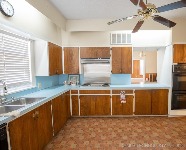 921 D NW, Ardmore, OK 73401 - kitchen featuring brown cabinetry, under cabinet range hood, ceiling fan, and plenty of natural light