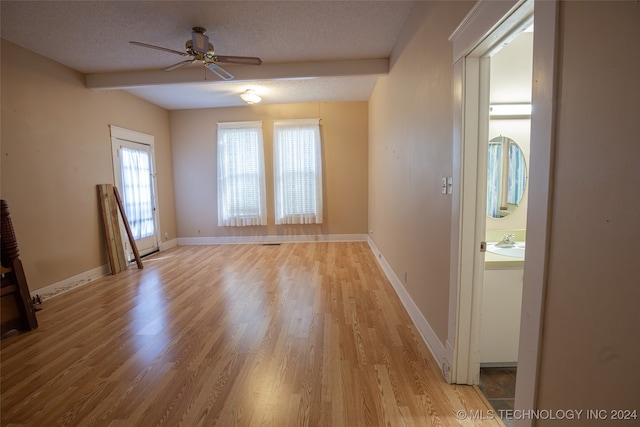 interior space with beamed ceiling, ceiling fan, a textured ceiling, and light wood-type flooring