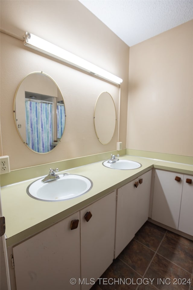 bathroom with tile patterned flooring, vanity, and a textured ceiling