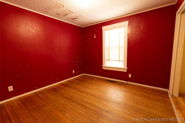 spare room with hardwood / wood-style floors, crown molding, and a textured ceiling