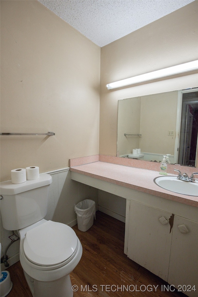 bathroom featuring toilet, vanity, hardwood / wood-style floors, and a textured ceiling