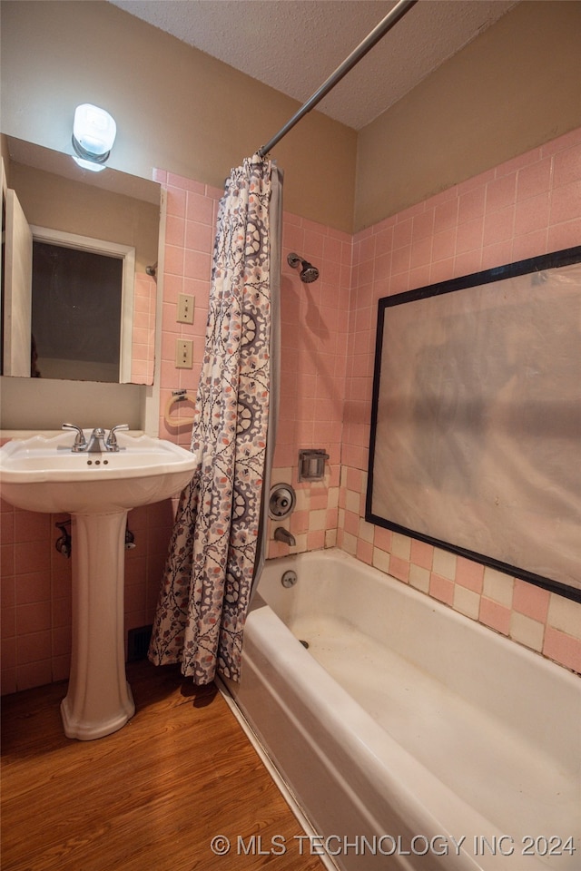 bathroom with hardwood / wood-style floors, a textured ceiling, sink, and shower / bathtub combination with curtain