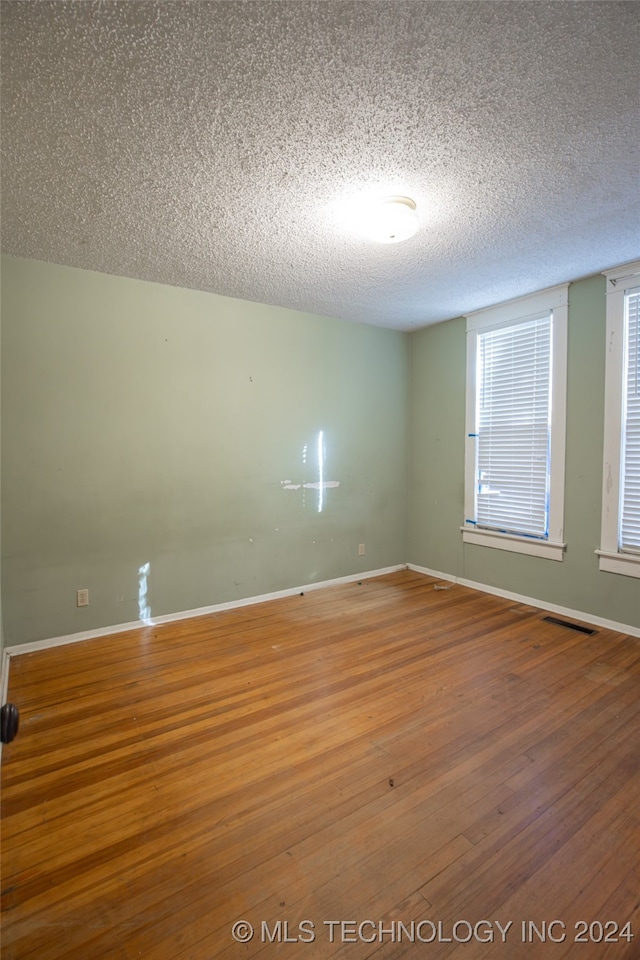 empty room with wood-type flooring and a textured ceiling