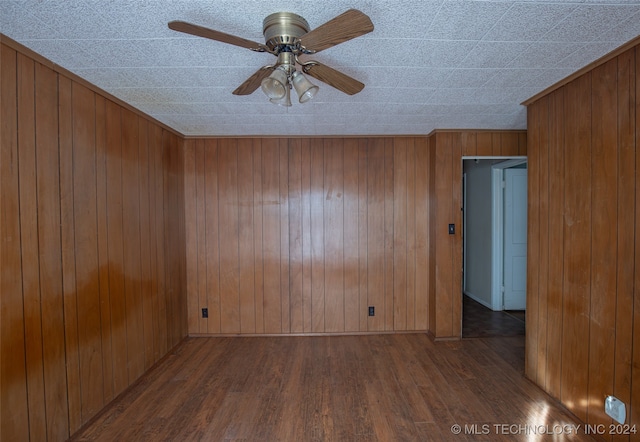 unfurnished room featuring hardwood / wood-style floors, ceiling fan, and wooden walls