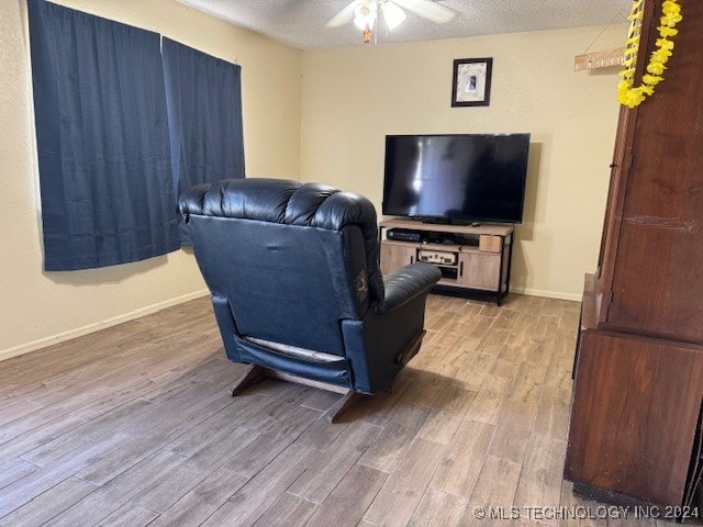 living room with ceiling fan, a textured ceiling, and hardwood / wood-style floors