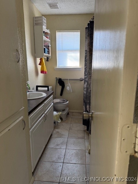 bathroom featuring toilet, tile patterned flooring, a shower with curtain, vanity, and a textured ceiling