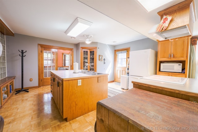 kitchen featuring white appliances, light parquet floors, plenty of natural light, and a kitchen island