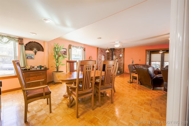 dining area with ceiling fan, brick wall, a wood stove, and light parquet floors