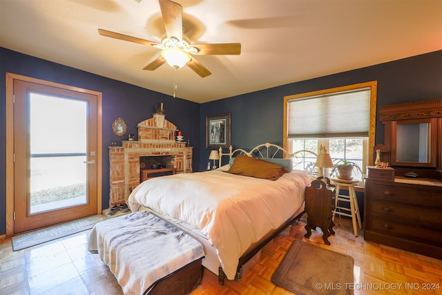 bedroom featuring parquet flooring, a brick fireplace, and ceiling fan