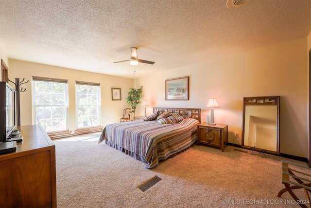 bedroom featuring a textured ceiling, light colored carpet, and ceiling fan