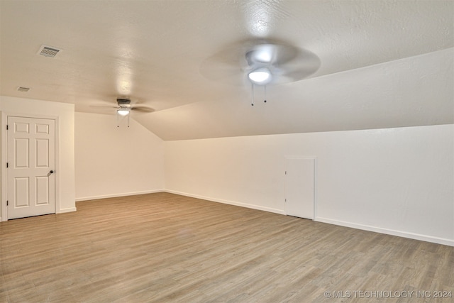 additional living space featuring vaulted ceiling, a textured ceiling, light hardwood / wood-style flooring, and ceiling fan