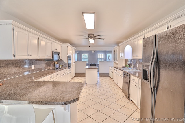 kitchen featuring decorative backsplash, kitchen peninsula, black appliances, white cabinets, and ceiling fan