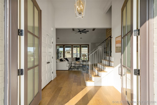 foyer entrance featuring french doors, wood-type flooring, and ceiling fan with notable chandelier