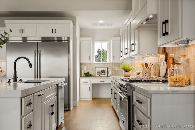 kitchen featuring custom exhaust hood, stainless steel range, light wood-type flooring, and white cabinets