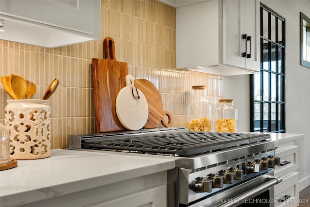 kitchen with tasteful backsplash, high end stainless steel range oven, plenty of natural light, and white cabinets