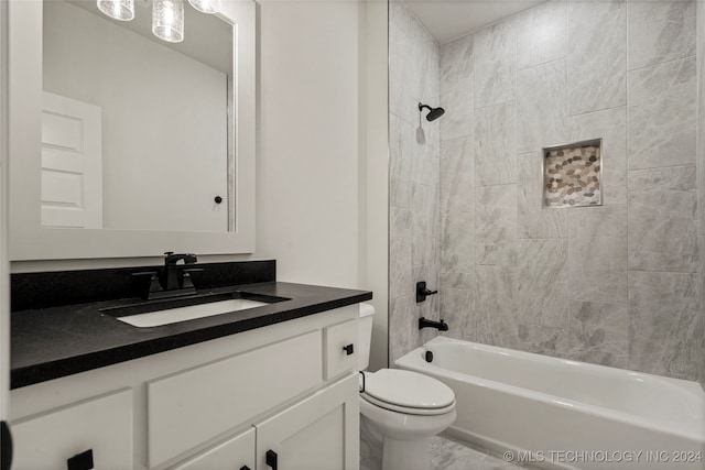 full bathroom featuring tiled shower / bath, vanity, and toilet