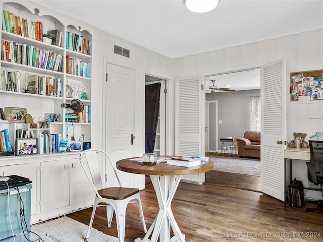 dining space with wood walls, hardwood / wood-style flooring, and ceiling fan