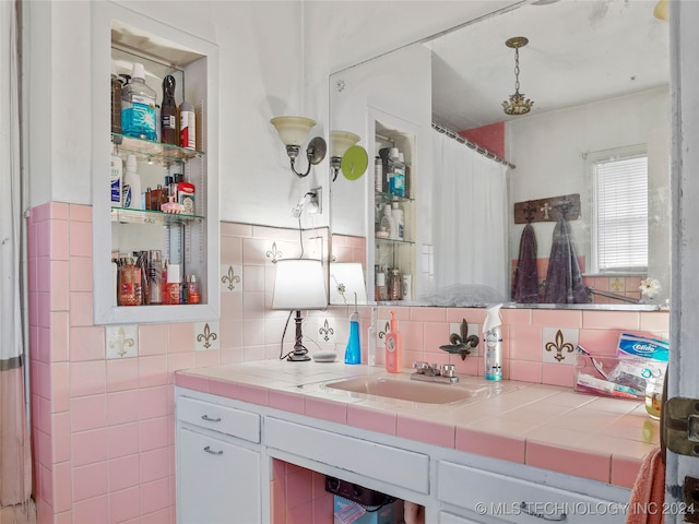 kitchen featuring tile counters, hanging light fixtures, sink, white cabinetry, and tasteful backsplash