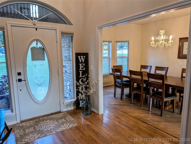 entryway with wood-type flooring and an inviting chandelier