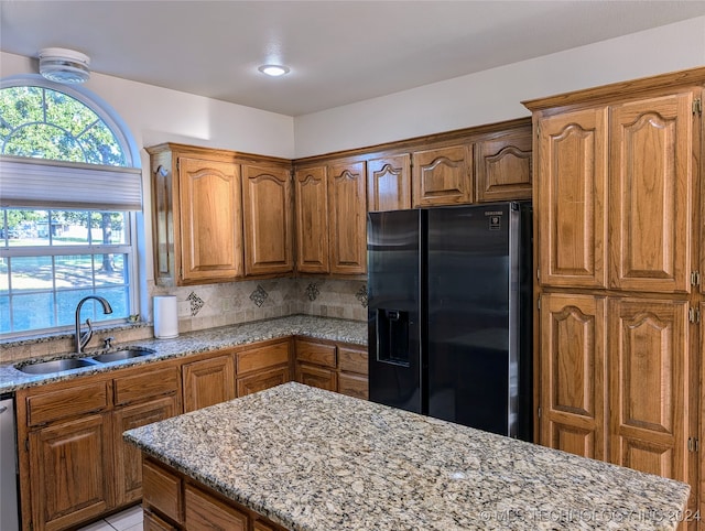 kitchen with fridge with ice dispenser, light stone counters, backsplash, stainless steel dishwasher, and sink