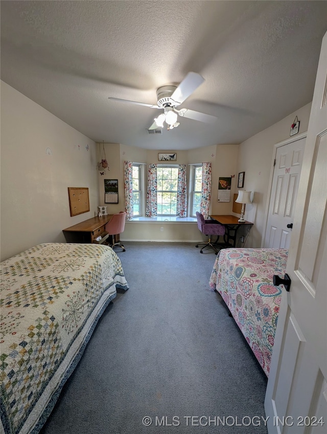 carpeted bedroom with ceiling fan and a textured ceiling