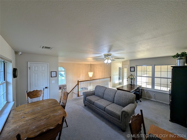 carpeted living room with ceiling fan, a textured ceiling, and plenty of natural light