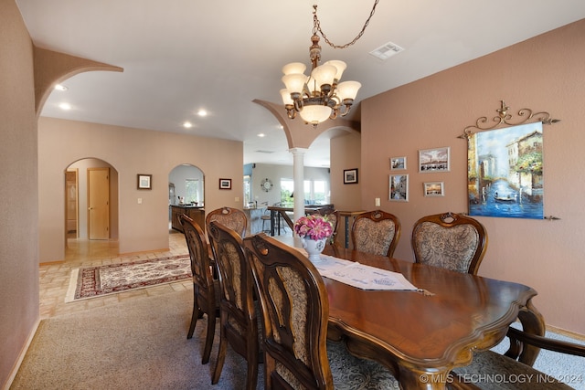 carpeted dining space featuring a notable chandelier and ornate columns