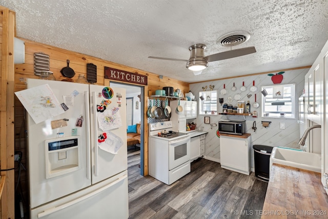 kitchen featuring dark hardwood / wood-style flooring, ceiling fan, white cabinetry, wooden walls, and white appliances