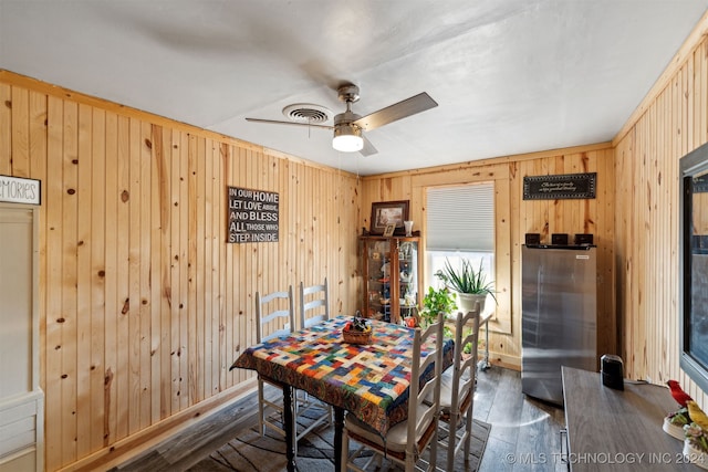 dining space with ceiling fan, wooden walls, and dark hardwood / wood-style flooring