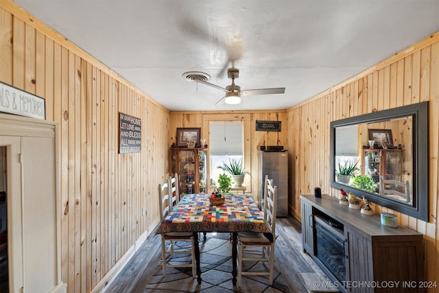 dining space featuring wood walls, ceiling fan, and dark hardwood / wood-style flooring