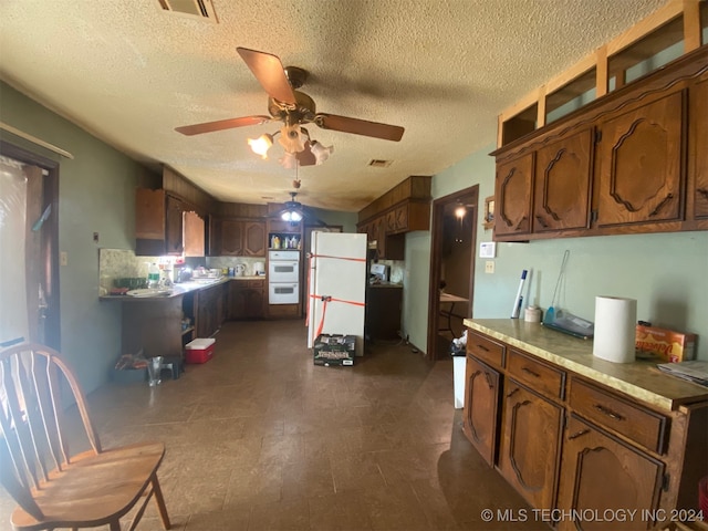 kitchen with ceiling fan, white appliances, a textured ceiling, and tasteful backsplash