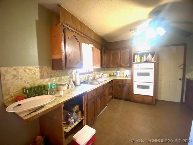 kitchen with backsplash, sink, ceiling fan, a textured ceiling, and double oven