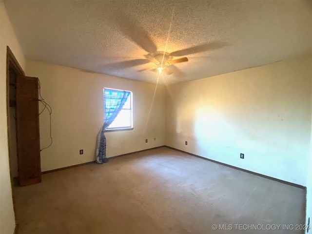 spare room featuring carpet, a textured ceiling, and ceiling fan