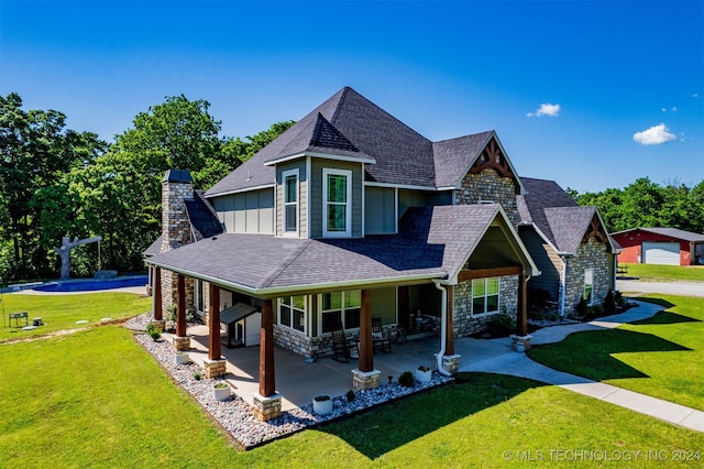 view of front of property with an outdoor structure, a garage, a front lawn, and a patio