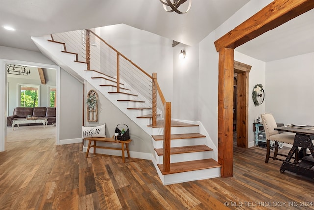 staircase with a notable chandelier and wood-type flooring