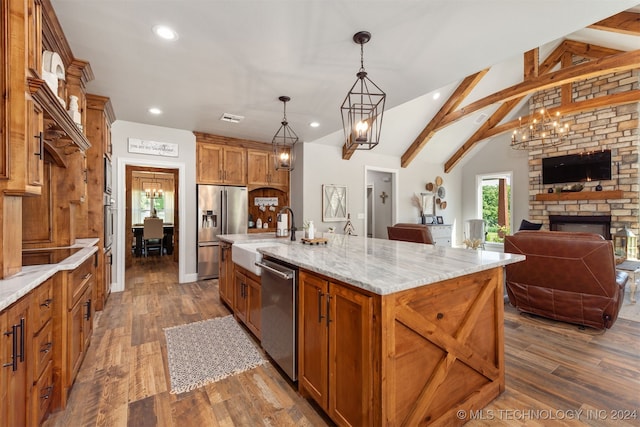 kitchen with a spacious island, appliances with stainless steel finishes, decorative light fixtures, and vaulted ceiling with beams