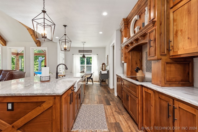 kitchen featuring an inviting chandelier, a kitchen island with sink, hardwood / wood-style flooring, black electric stovetop, and decorative light fixtures